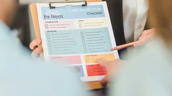 Hands holding a home inspection checklist on a clipboard