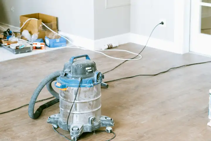 Wet and dry shop vacuum on a bare floor in a room under repair