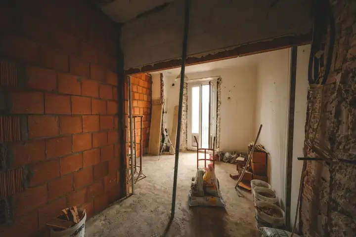Room under repair with exposed brick walls and building materials on the floor