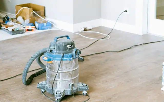 Wet and dry shop vacuum on a bare floor in a room under repair